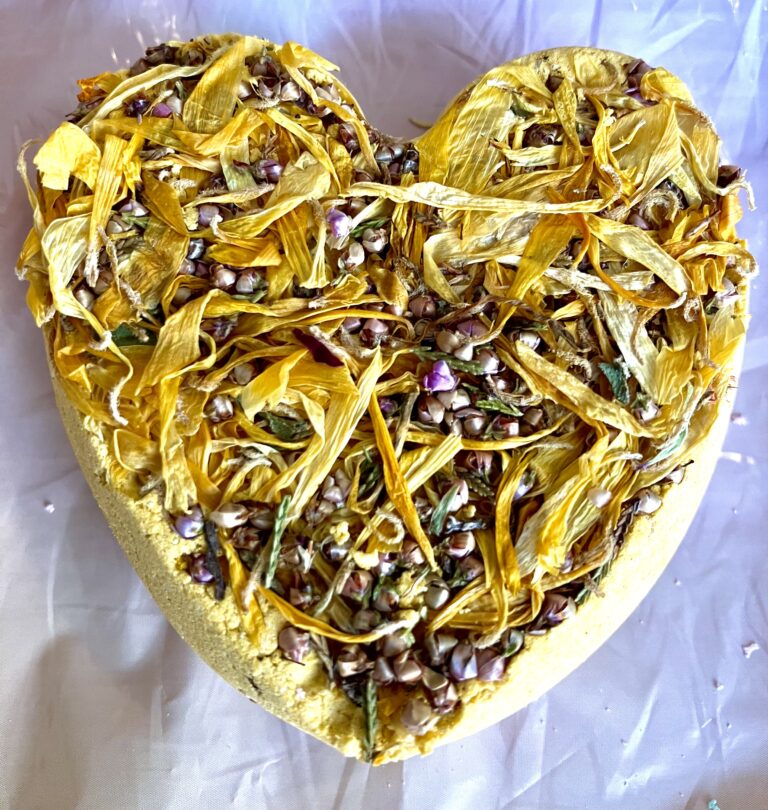 Heart shaped yellow bath-bomb, decorated and scented with marigold flowers and heather flowers