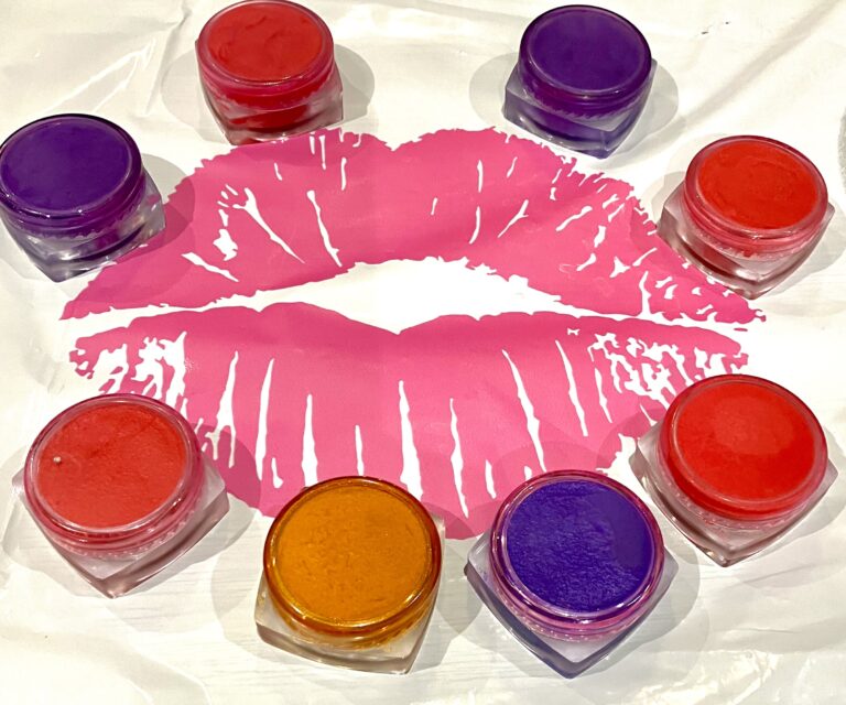Eight different coloured lip glosses placed around the outside of a picture of a pair of pink lips.